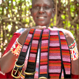 Maasai woman showcasing her handmade beaded leather dog collars and leashes for The Maasai Collection featuring the pink and gold Flamingo design on black leather