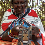 Maasai Mara Mama in traditional clothing showcasing her hand made dog collars for The Maasai Collection 