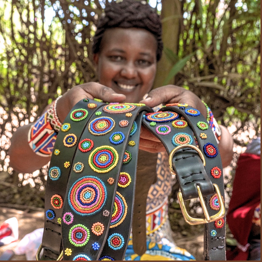 Maasai woman showcasing her handmade dog collars and leashes for The Maasai Collection featuring the multi-coloured Solaris design on black leather