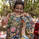Maasai woman showcasing her handmade dog collars and leashes for The Maasai Collection featuring the multi-coloured Solaris design on black leather